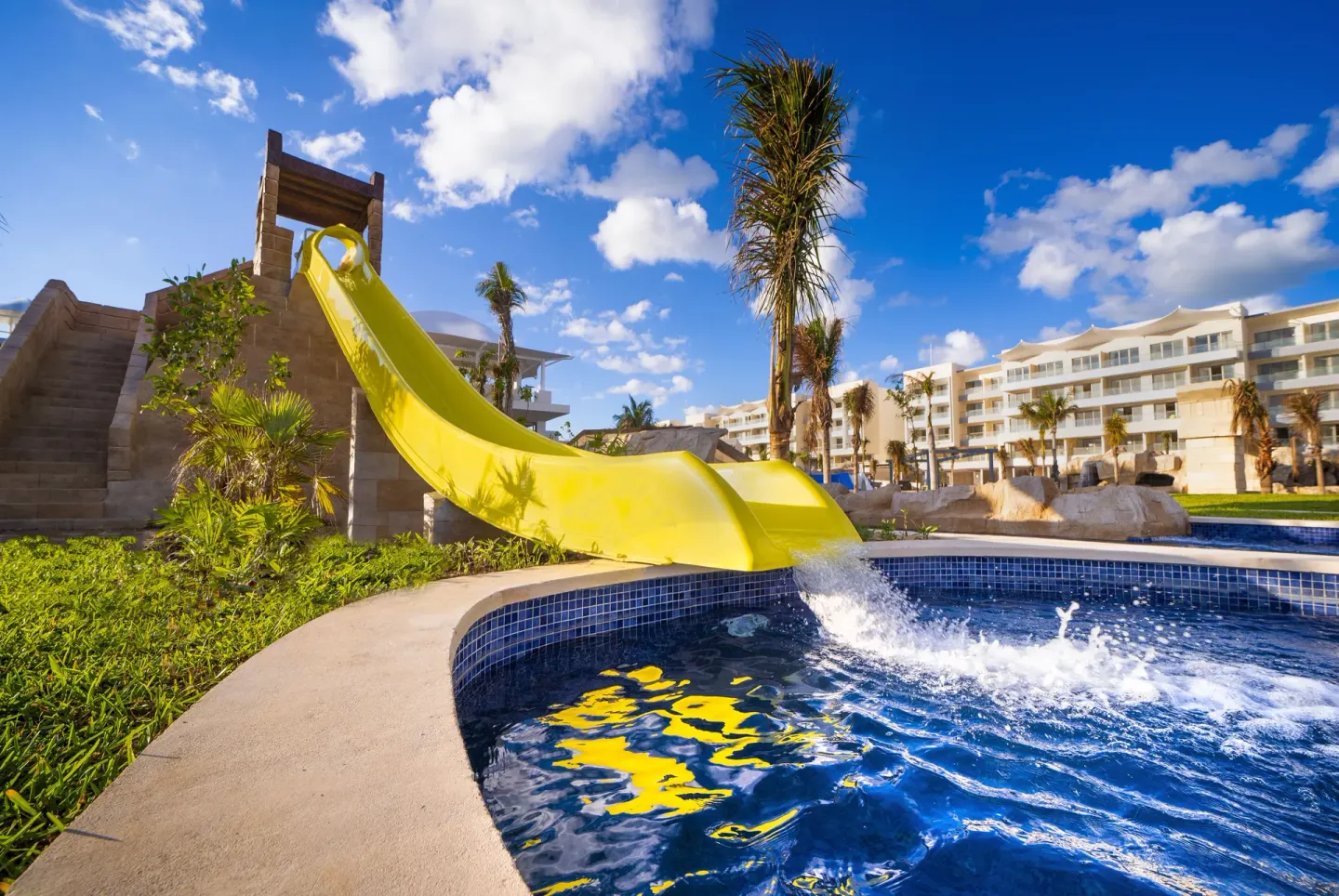 Yellow waterslide splashing into a pool at Planet Hollywood Cancun.