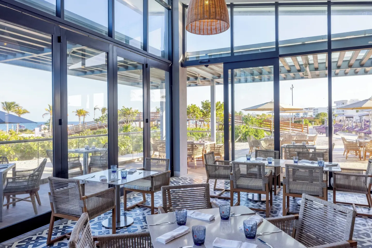 Bright beachfront dining room with set tables at Planet Hollywood Cancun.