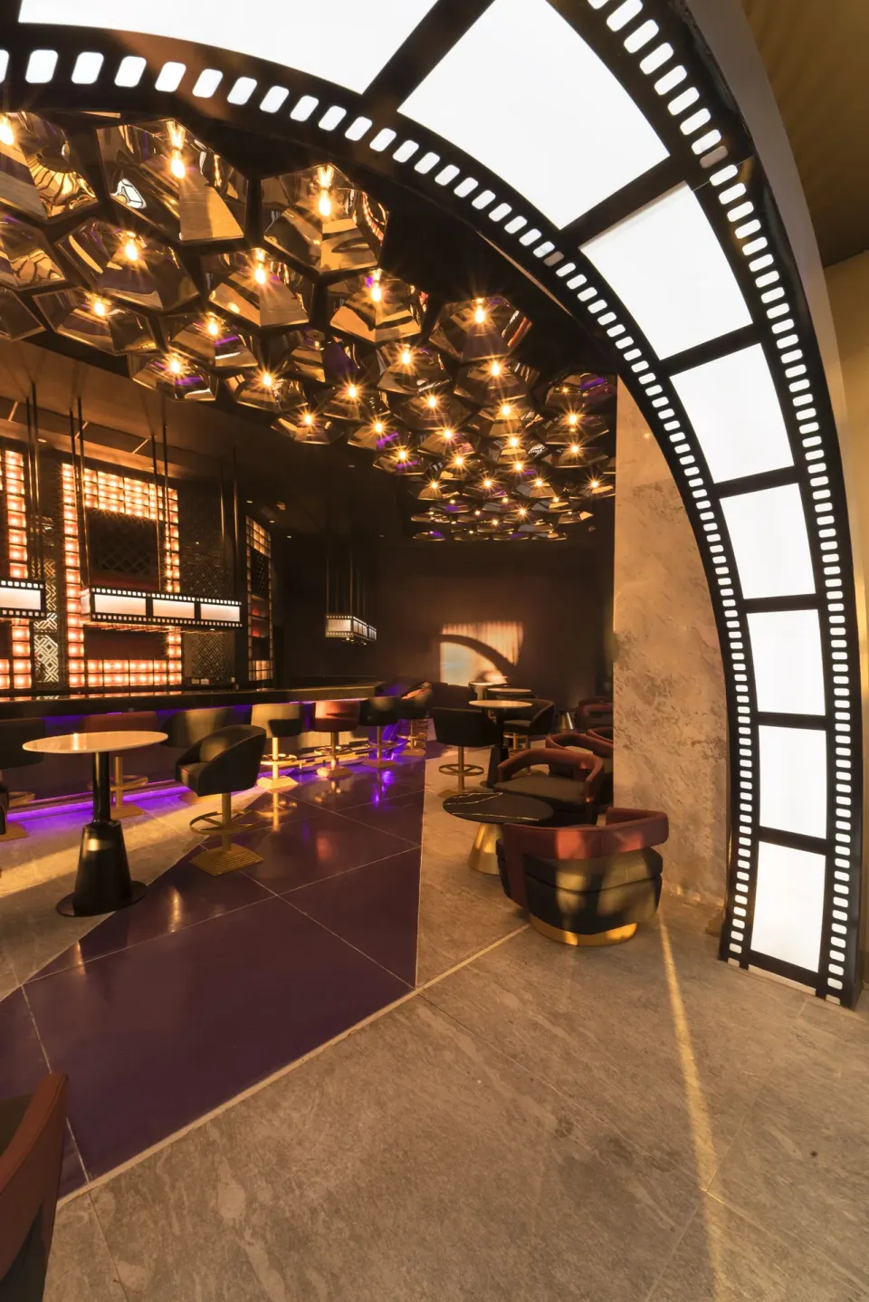Filmstrip arch frames a lounge with tables and warm ceiling lights at Planet Hollywood Cancun.