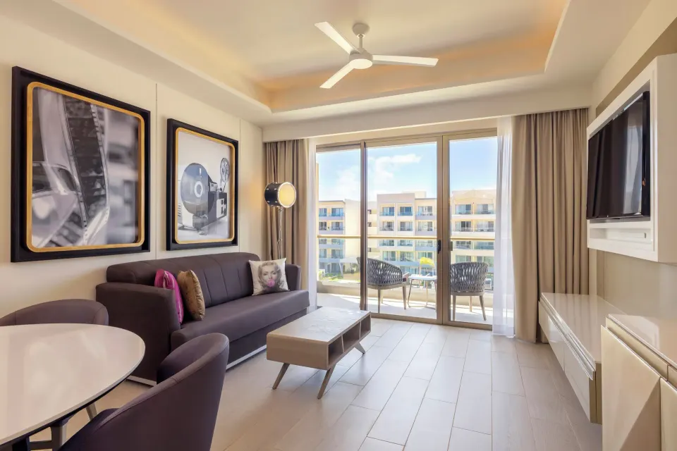 Directors Suite One Bedroom lounge with sofa, dining table and balcony at Planet Hollywood Cancun.