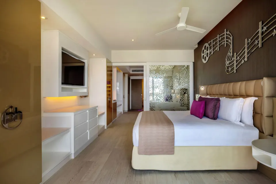 Entourage Suite king bed, TV wall, and glass bathroom partition at Planet Hollywood Cancun.