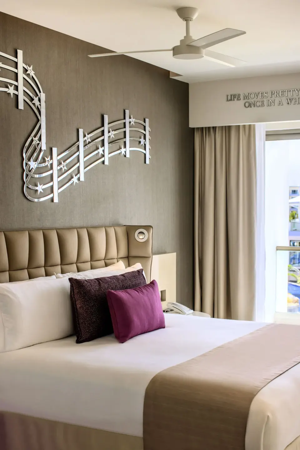 Entourage Suite king bed with wall art and balcony light at Planet Hollywood Cancun.