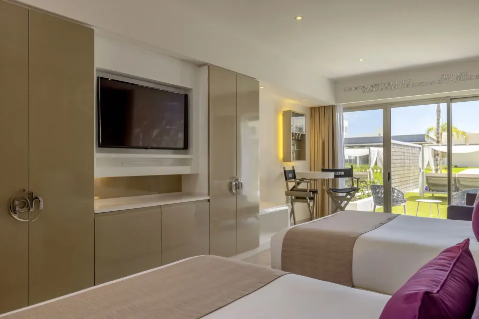 Two beds, TV wall, and patio doors in the Junior Suite Swim Out at Planet Hollywood Cancun.