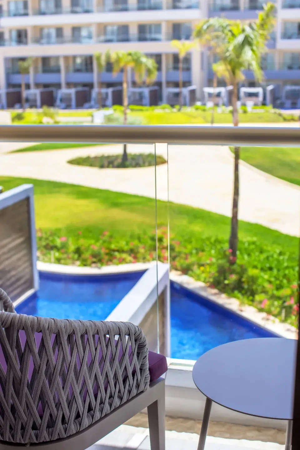 Junior Suite balcony seating overlooking palms and pools at Planet Hollywood Cancun.