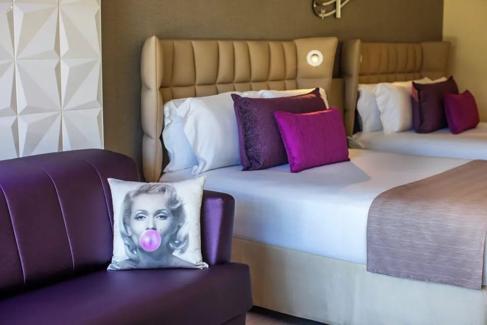 Junior Suite two beds with purple sofa and accent pillows at Planet Hollywood Cancun.