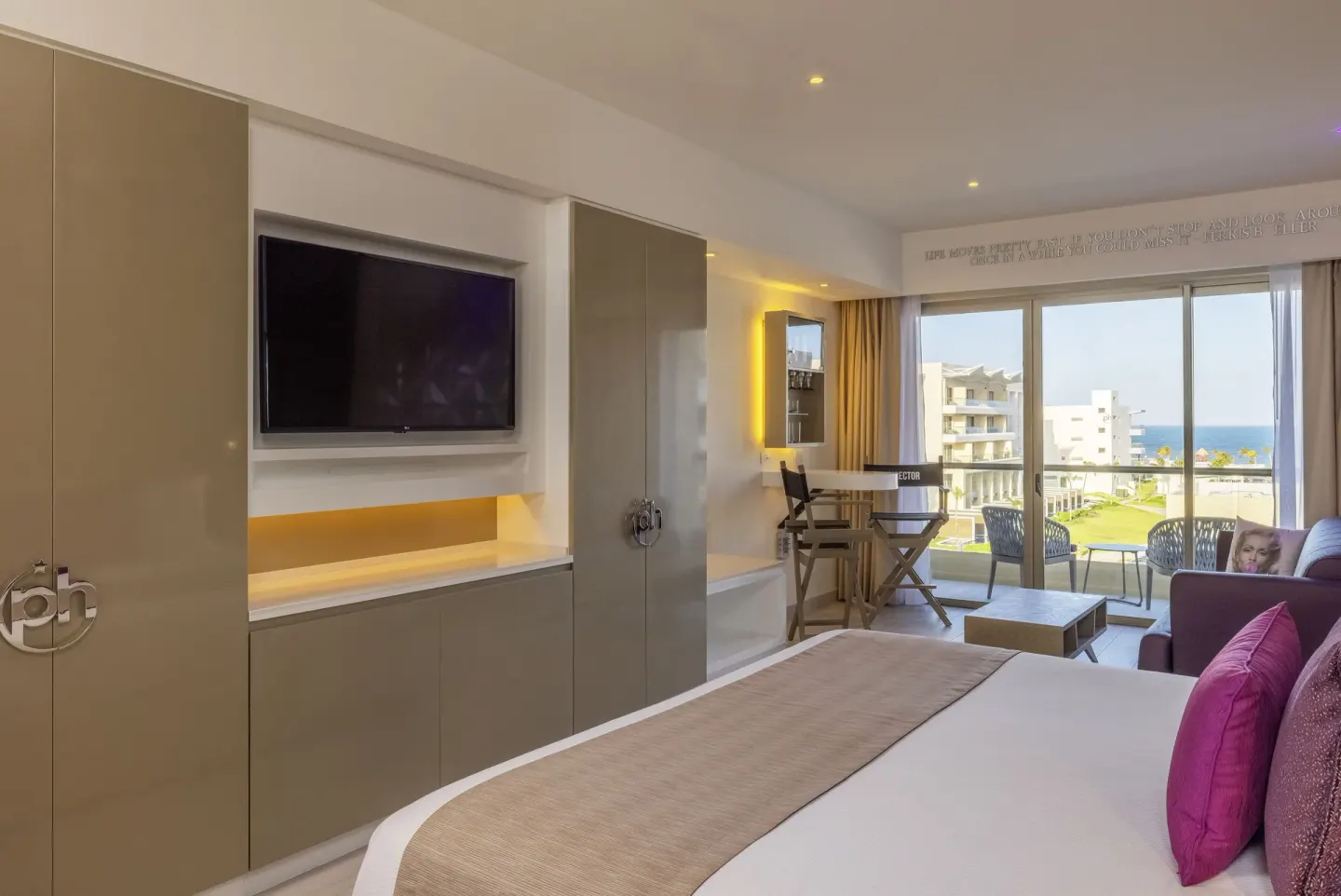 Star Class Junior Suite bed, TV wall, sitting area, and balcony ocean view at Planet Hollywood Cancun.