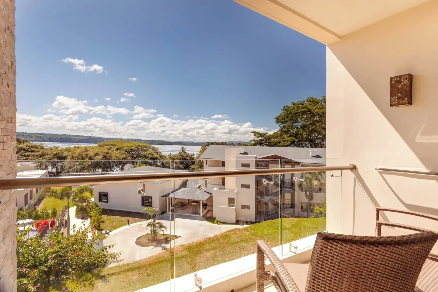 Balcony with glass railing overlooking resort buildings and the bay at Planet Hollywood Costa Rica.