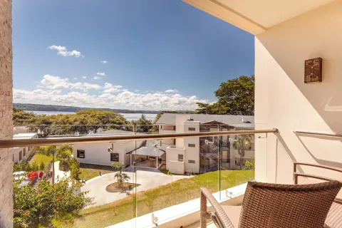 Balcony with glass railing overlooking resort buildings and the bay at Planet Hollywood Costa Rica.