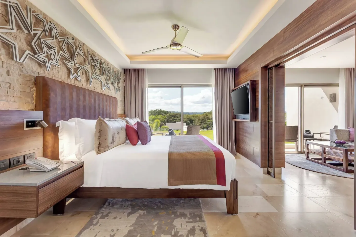 King bed guest room with star wall decor and balcony view at Planet Hollywood Costa Rica.