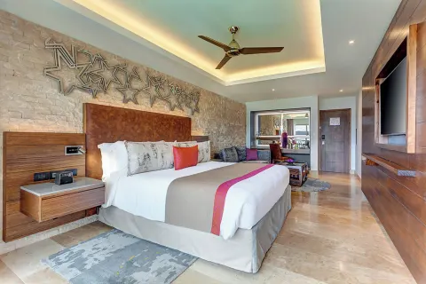 King bed guest room with star wall decor and seating area at Planet Hollywood Costa Rica.