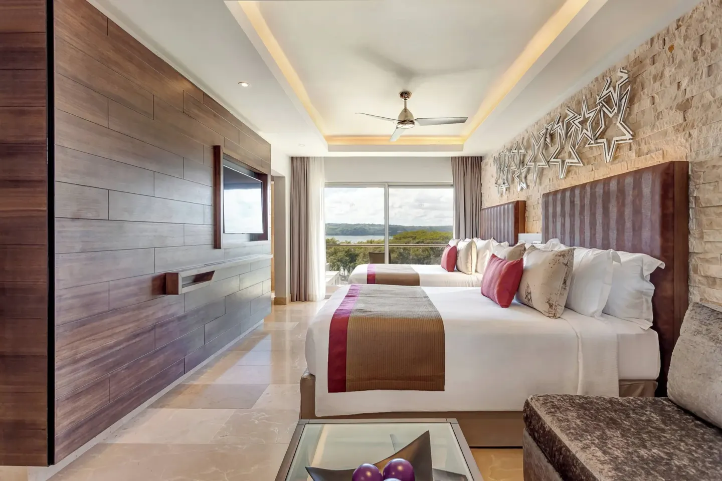 Two-bed guest room with sofa and balcony view at Planet Hollywood Costa Rica.