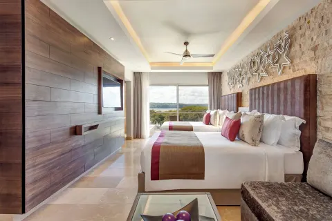 Two-bed guest room with sofa and balcony view at Planet Hollywood Costa Rica.
