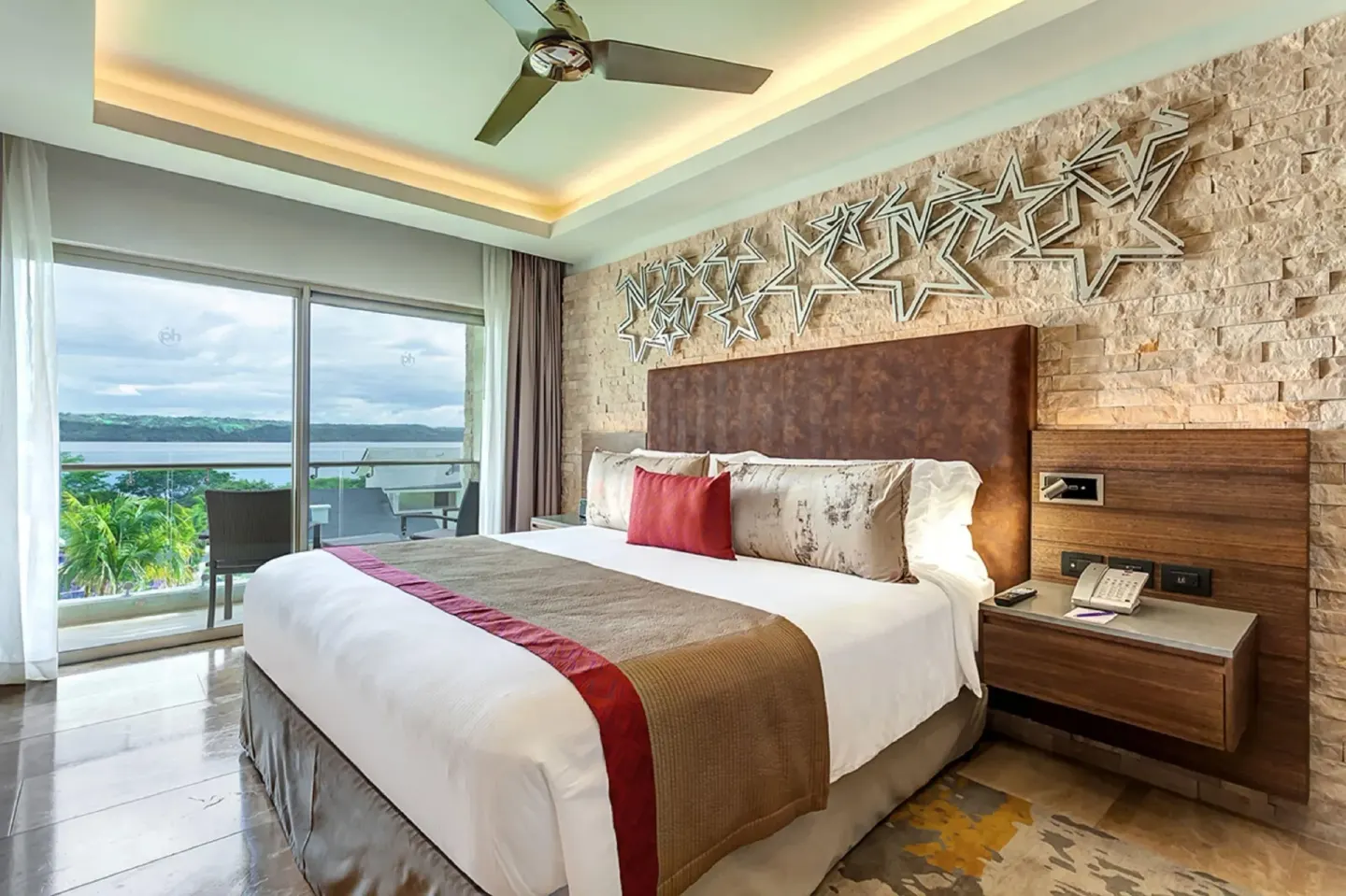 Guest room king bed with balcony and water view at Planet Hollywood Costa Rica.