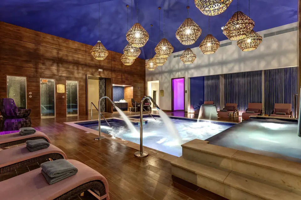 Indoor spa pool with lounge chairs and hanging lights at Planet Hollywood Costa Rica.