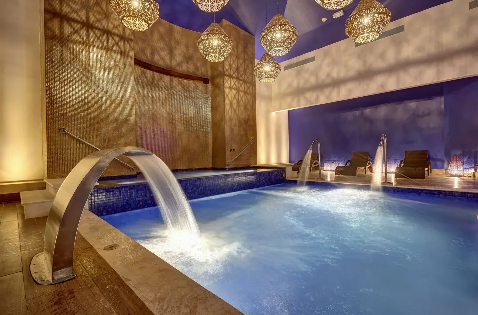 Indoor spa pool with waterfalls and lounge chairs at Planet Hollywood Costa Rica.