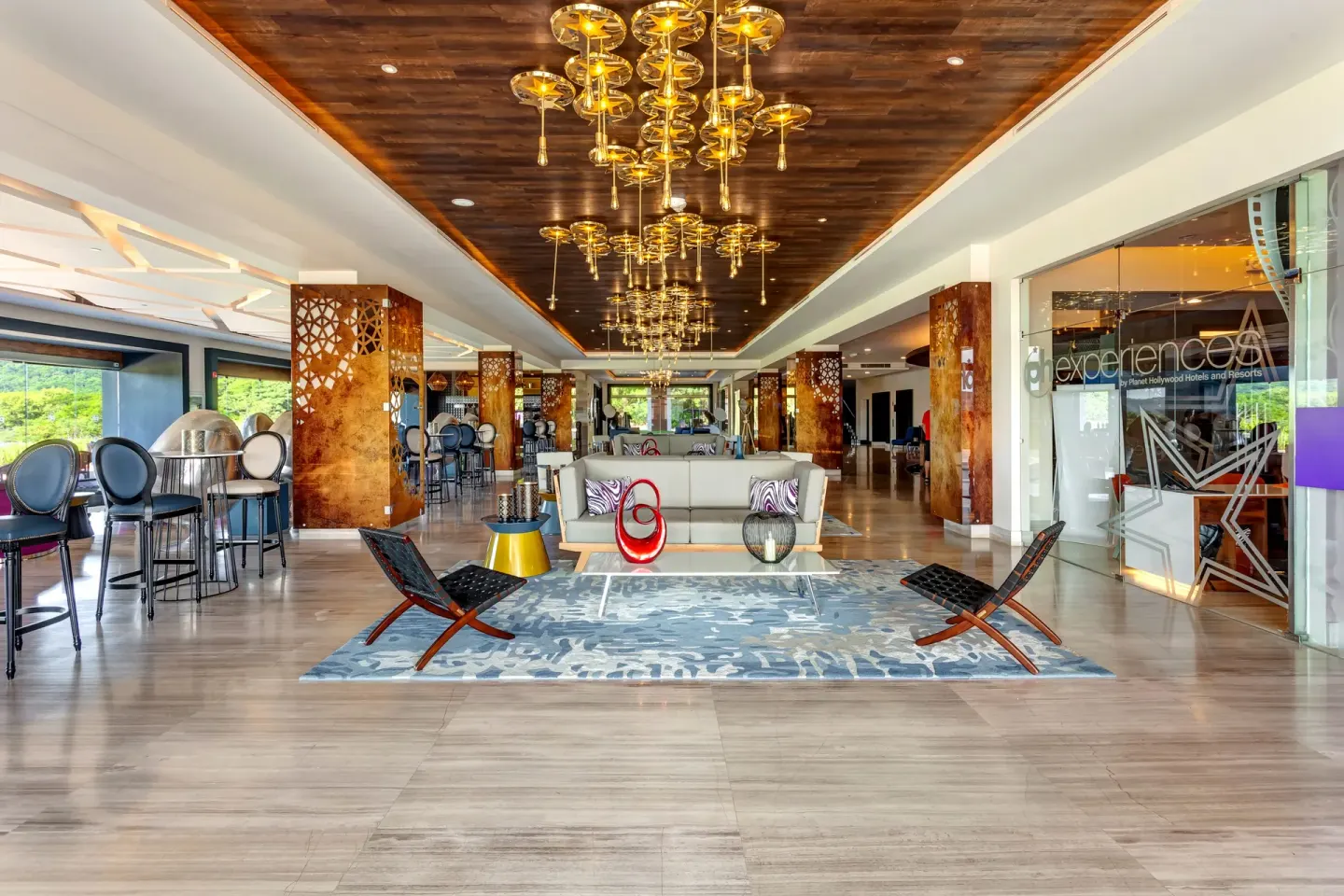 Lobby lounge with chandeliers and glass-walled office at Planet Hollywood Costa Rica.