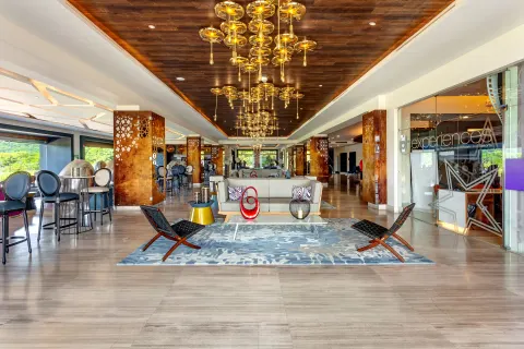 Lobby lounge with chandeliers and glass-walled office at Planet Hollywood Costa Rica.