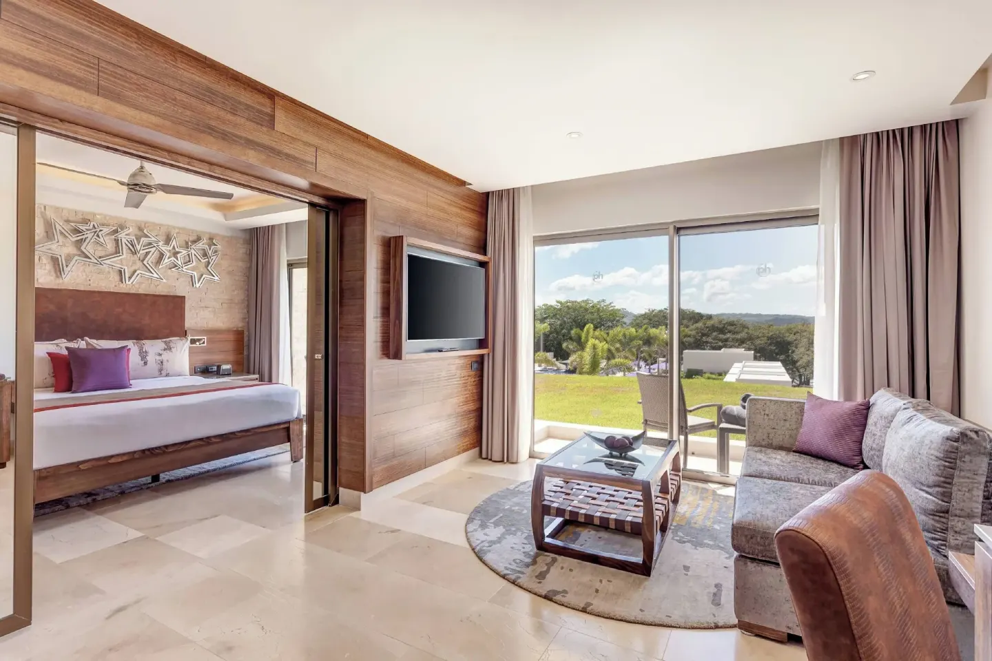 Suite living room with sofa, TV and separate king bedroom at Planet Hollywood Costa Rica.