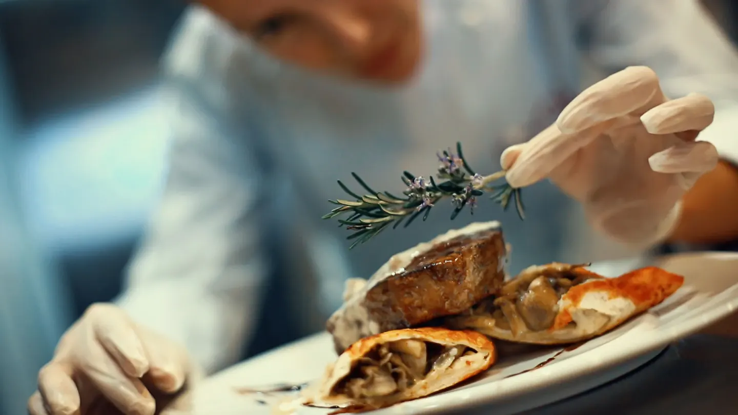 A chef garnishes a plated steak dish at Planet Hollywood Costa Rica.