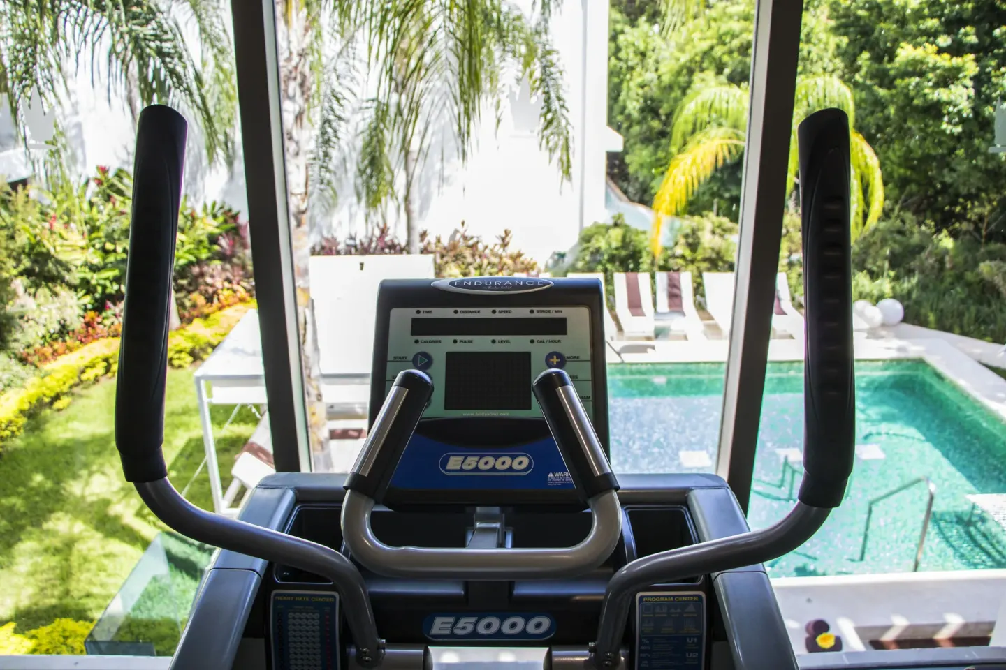 Elliptical machine by a window overlooking a small pool at Platinum Yucatan Princess.
