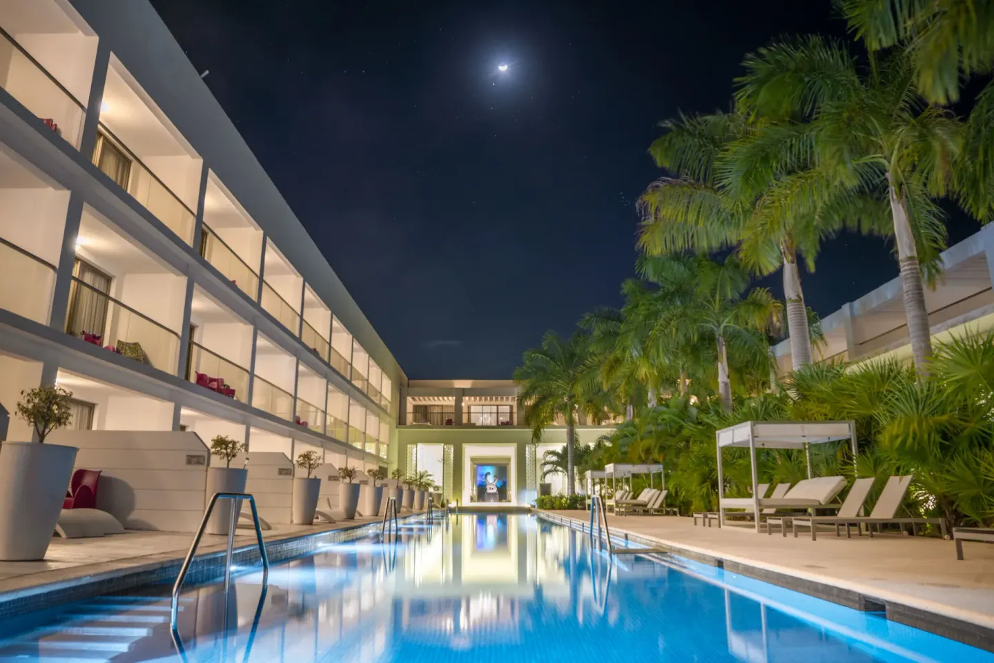 Moonlit swim-up pool courtyard with palms and loungers at Platinum Yucatan Princess.
