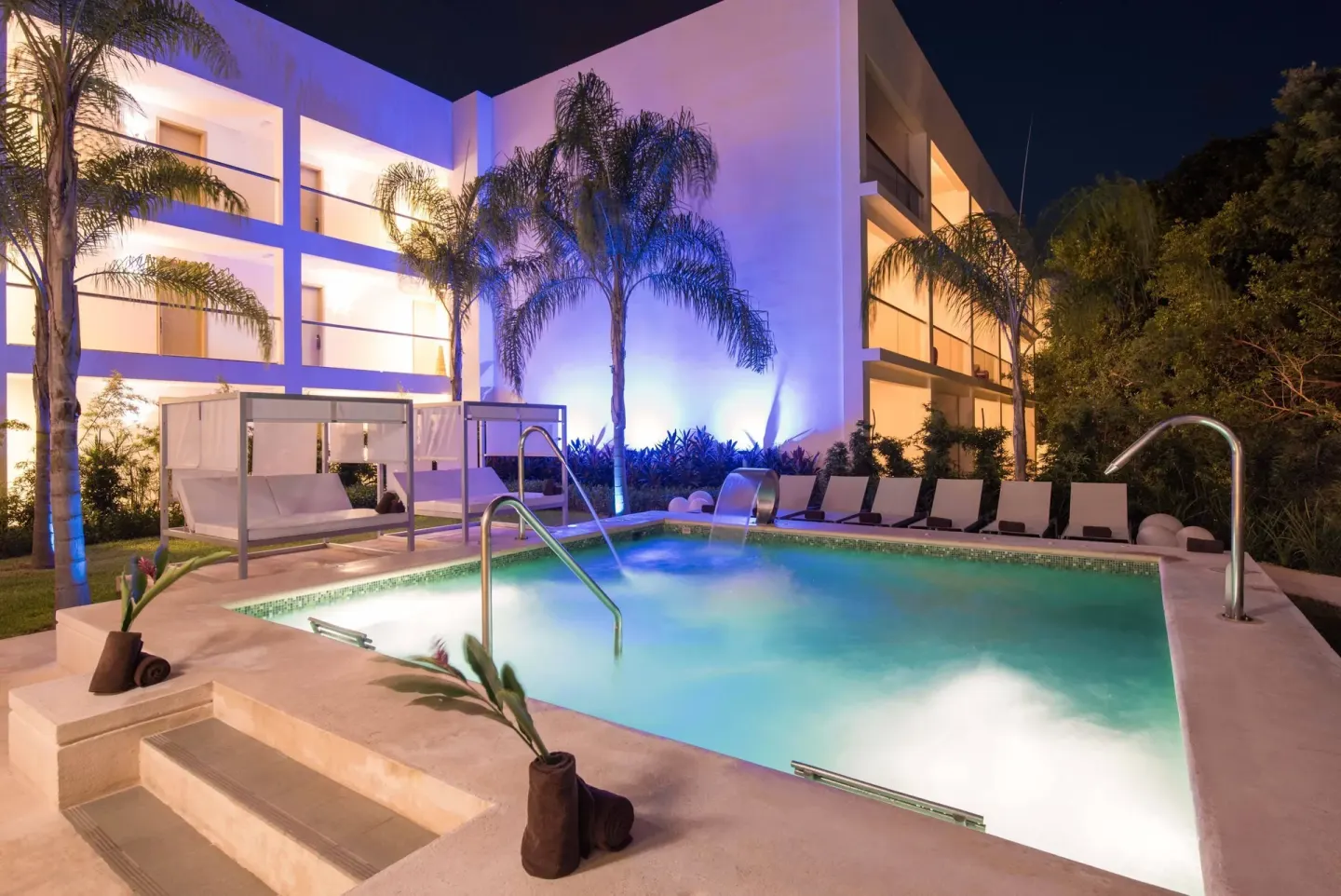 Illuminated pool with loungers and palms at Platinum Yucatan Princess.