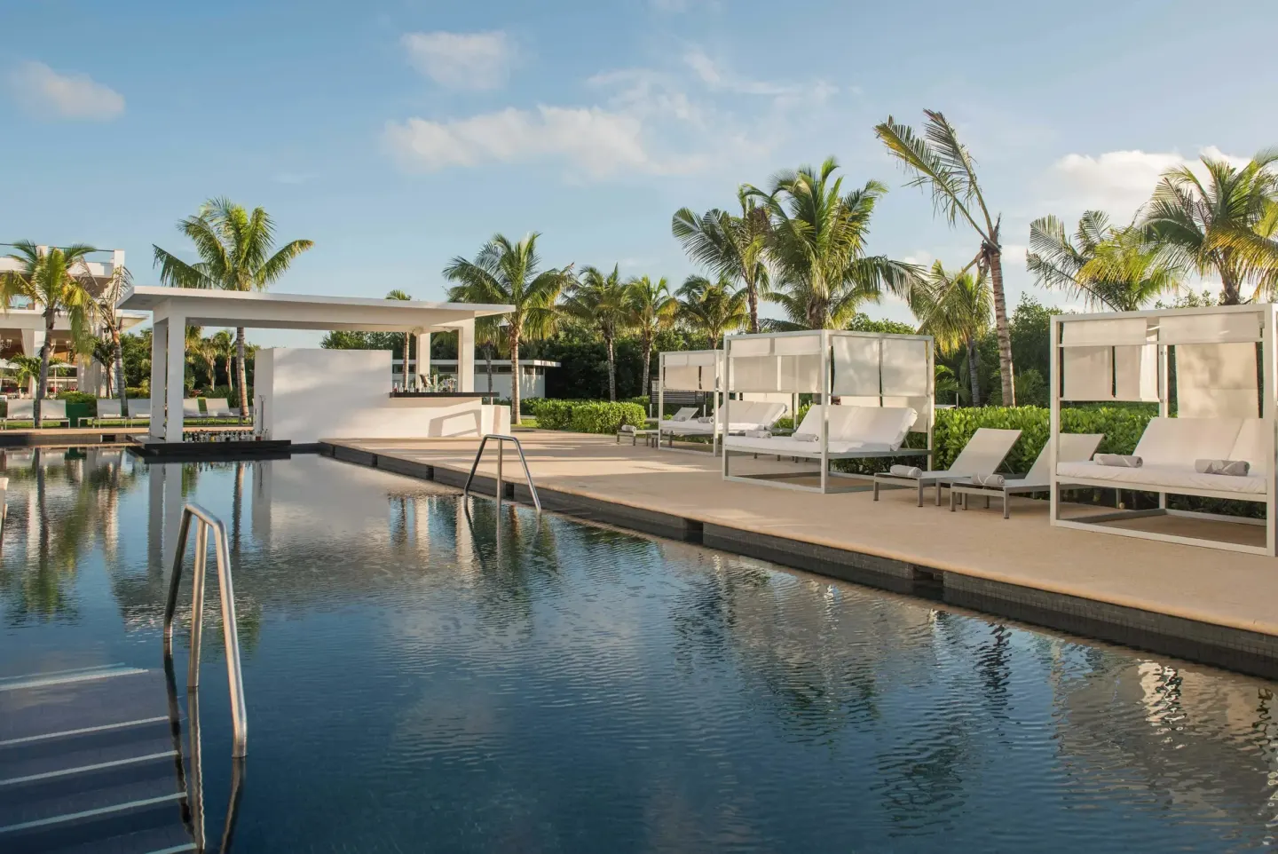 Pool with cabana daybeds and palm trees at Platinum Yucatan Princess.