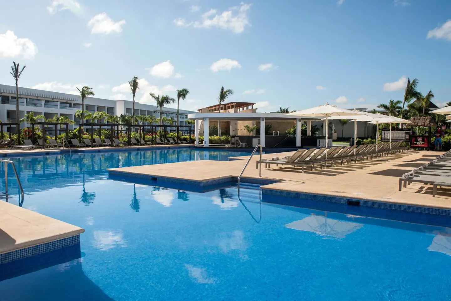 Pool deck with loungers, umbrellas and palm trees at Platinum Yucatan Princess.