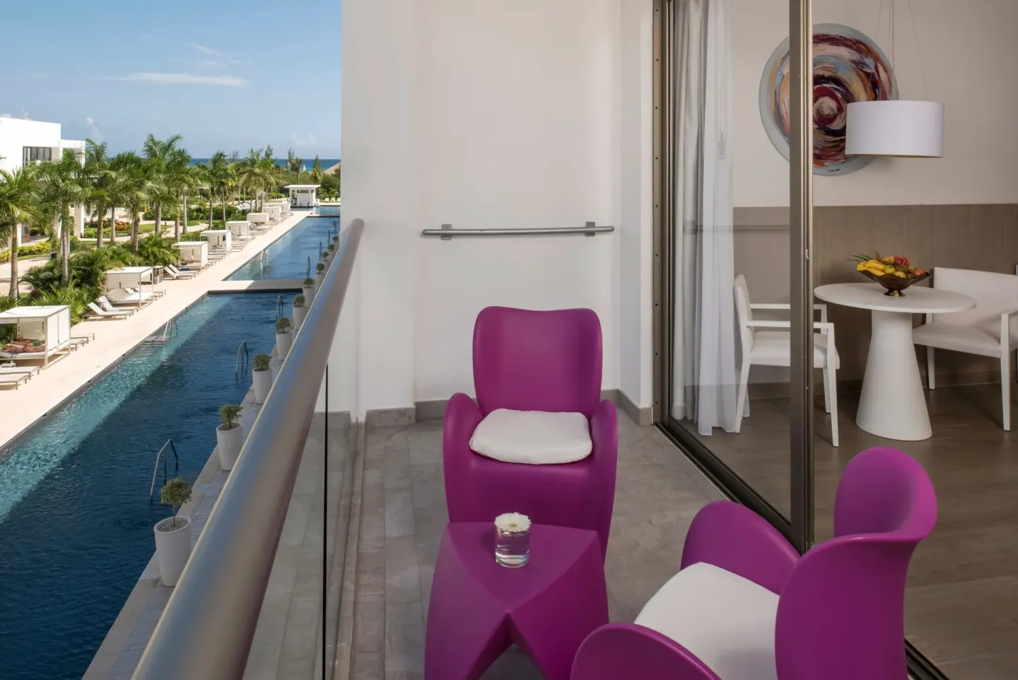 Balcony with magenta chairs overlooking a long pool at Platinum Yucatan Princess.