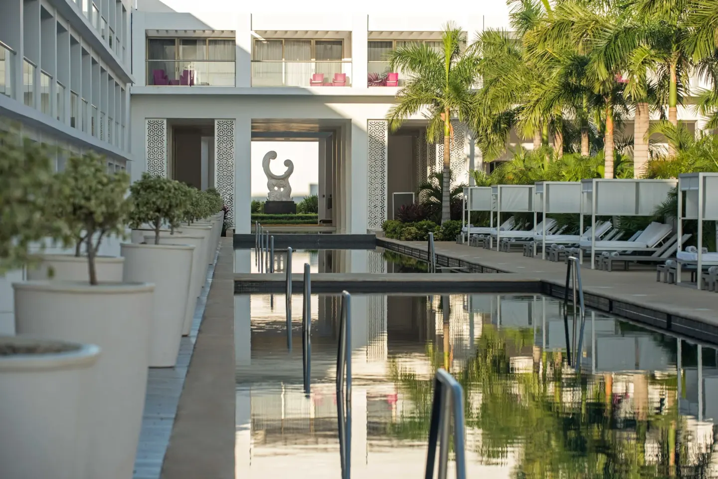 Quiet pool walkway with palms, planters and a sculpture at Platinum Yucatan Princess.