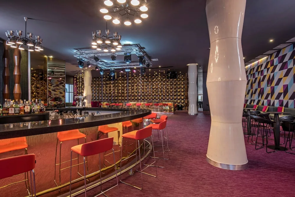 Curved bar with orange stools and stage lighting at Platinum Yucatan Princess.