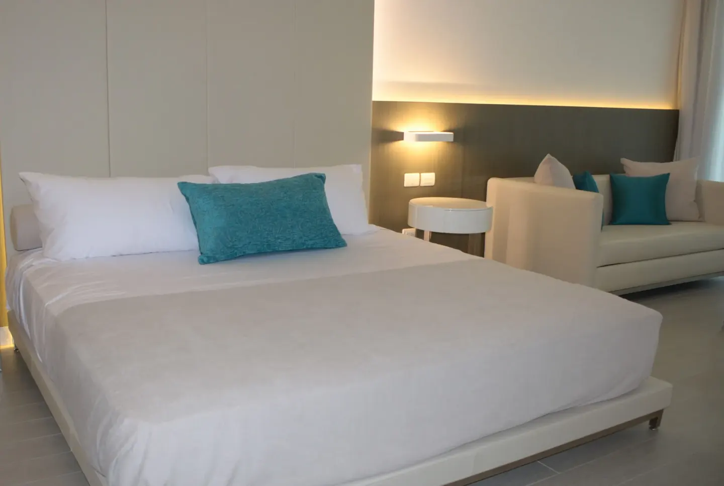 Junior Suite king bed beside a sofa sitting area at Platinum Yucatan Princess.