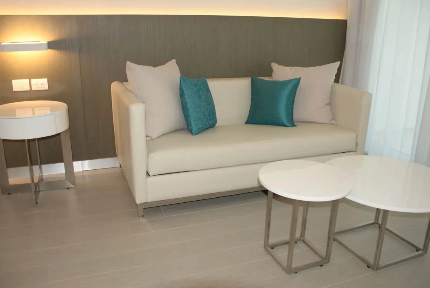 Junior Suite sofa lounge with pillows and round tables at Platinum Yucatan Princess.