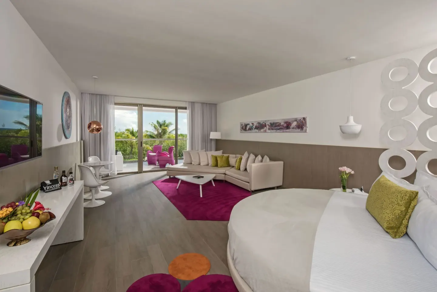 Wide view of a round bed suite with balcony and seating at Platinum Yucatan Princess.
