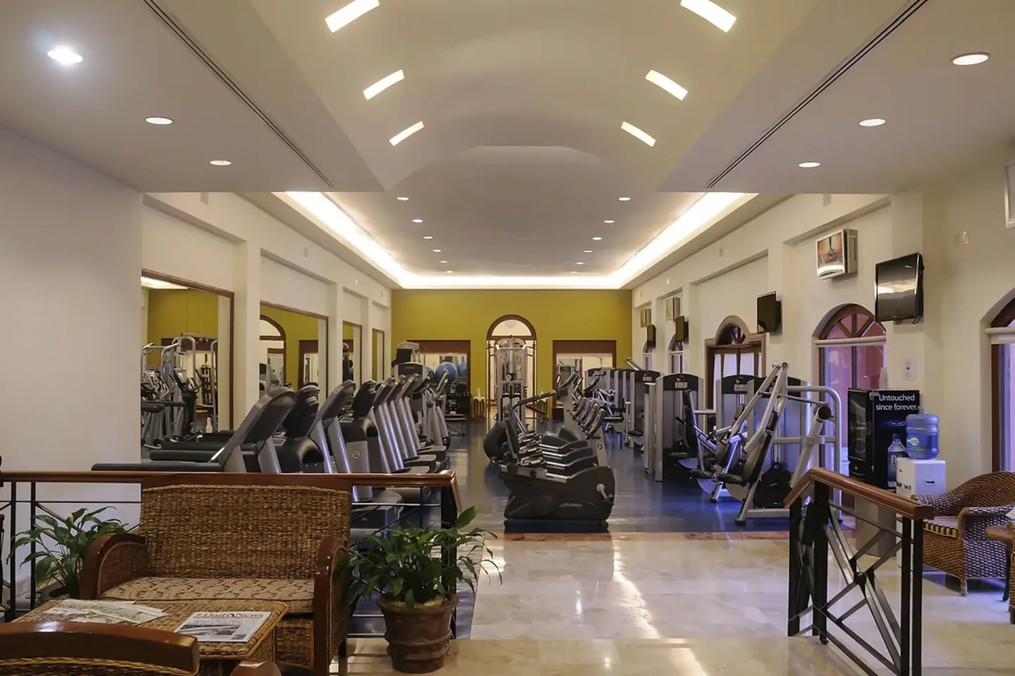 Fitness center entrance with cardio machines and seating at Playa Grande Resort & Grand Spa.