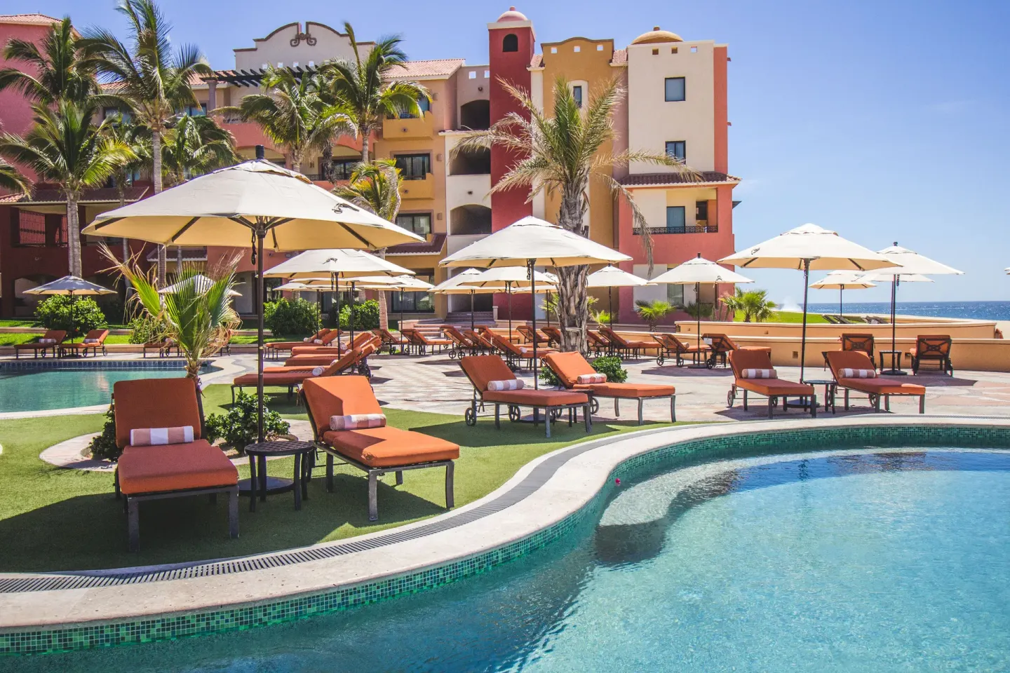 Poolside loungers and umbrellas near oceanfront buildings at Playa Grande Resort & Grand Spa.