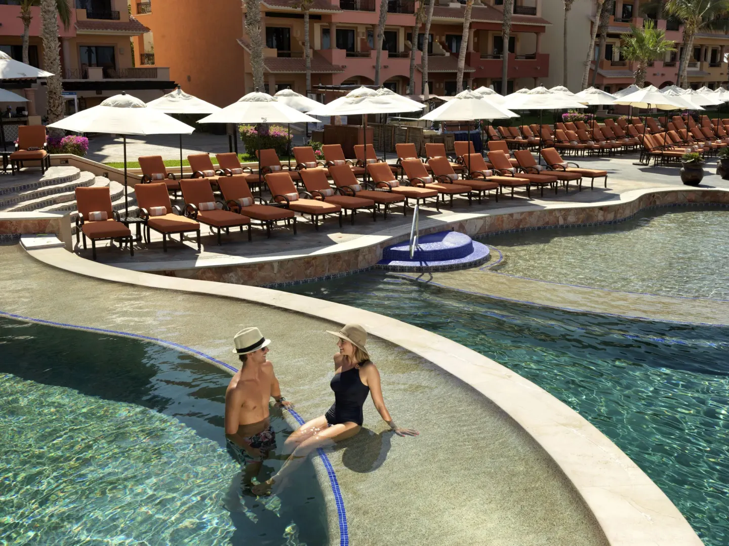 Guests stand in a shallow pool area with loungers behind them at Playa Grande Resort & Grand Spa.