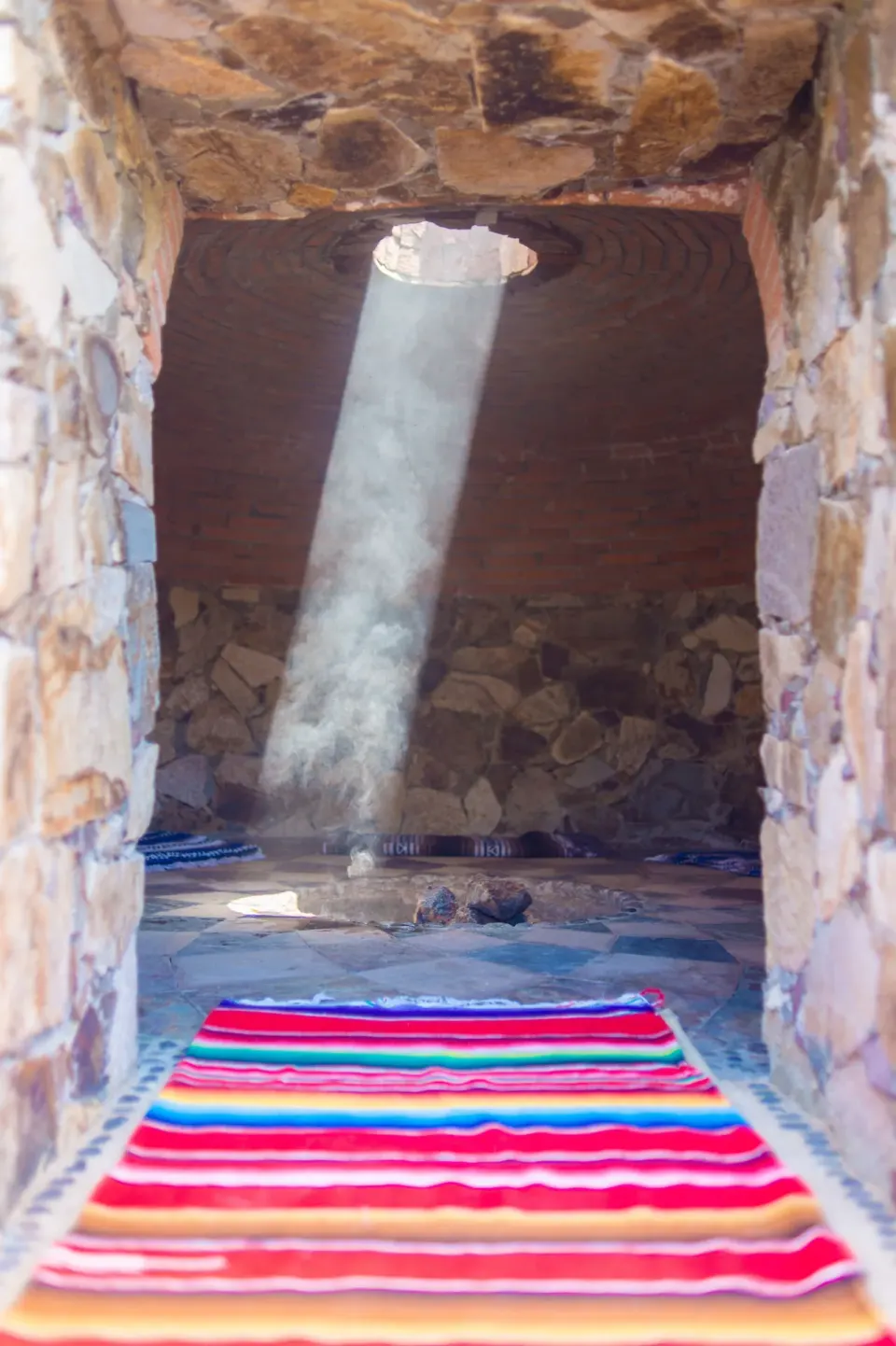 Stone spa chamber with sunlight beam and striped mat at Playa Grande Resort & Grand Spa.