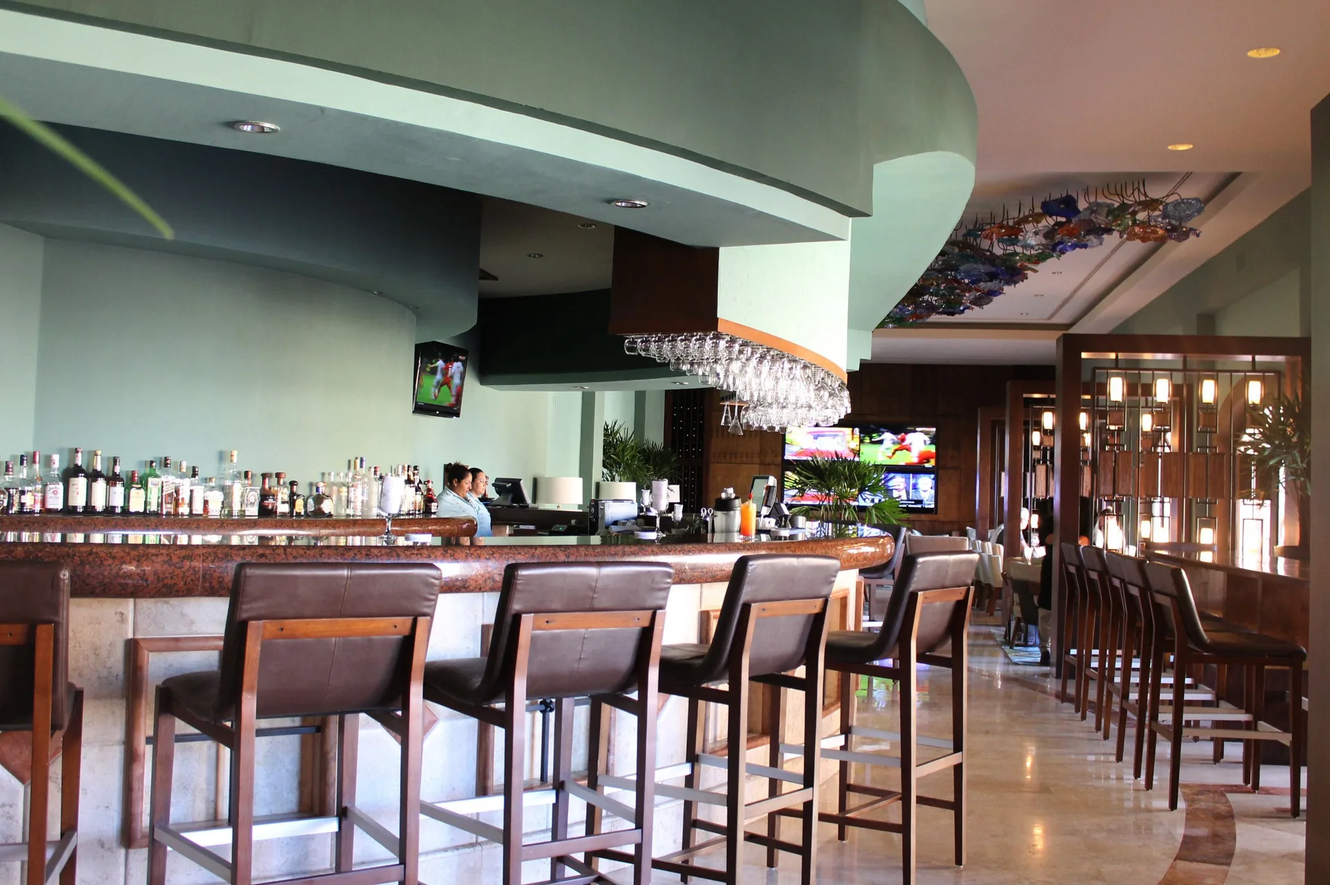 Bar counter with stools and TVs at Playa Grande Resort & Grand Spa.