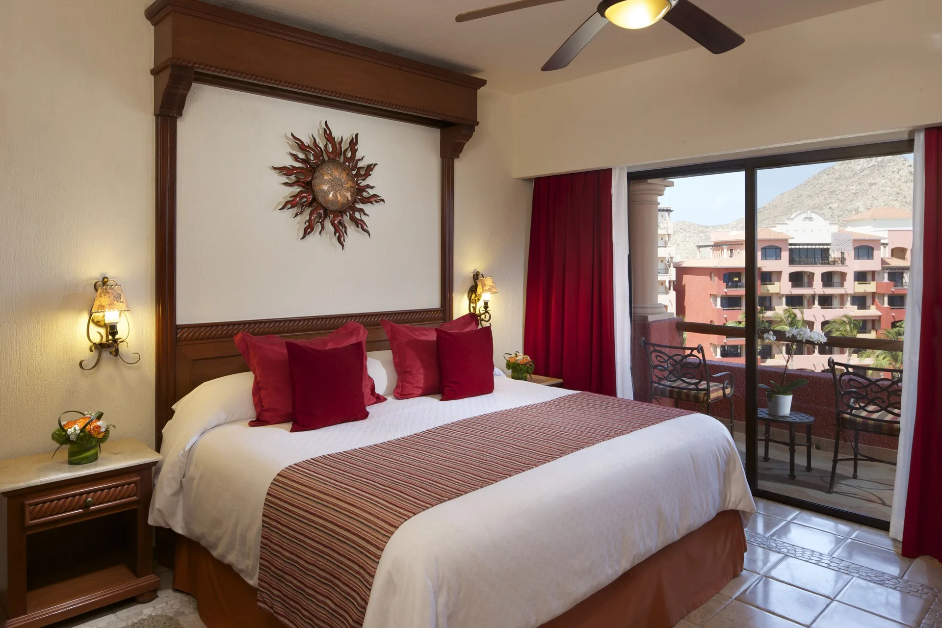 Luxury Suite one-bedroom king bed at Playa Grande Resort & Grand Spa with balcony doors and red accents.