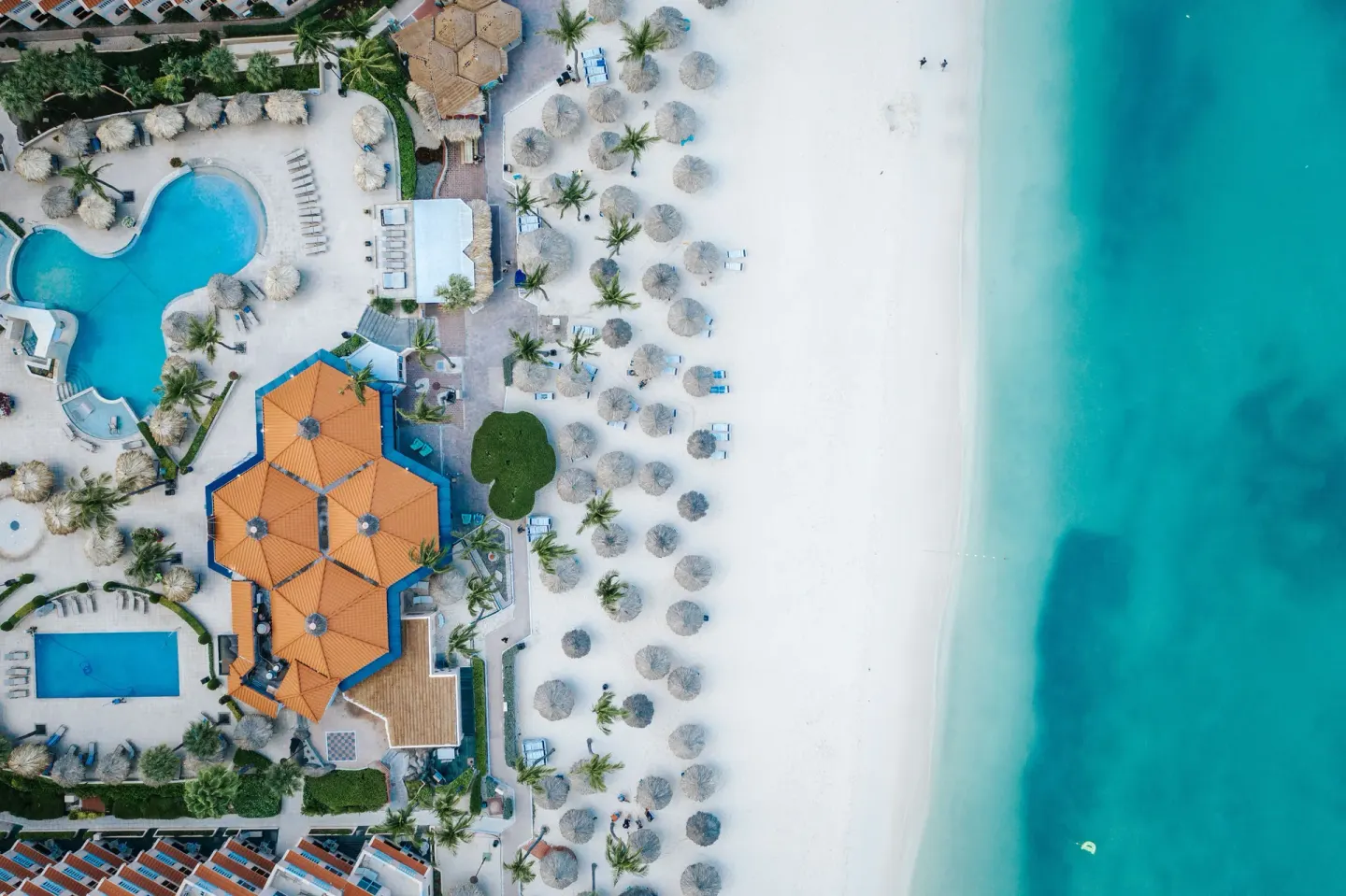 Aerial view of beach, pools, and palapas at Playa Linda Beach Resort.