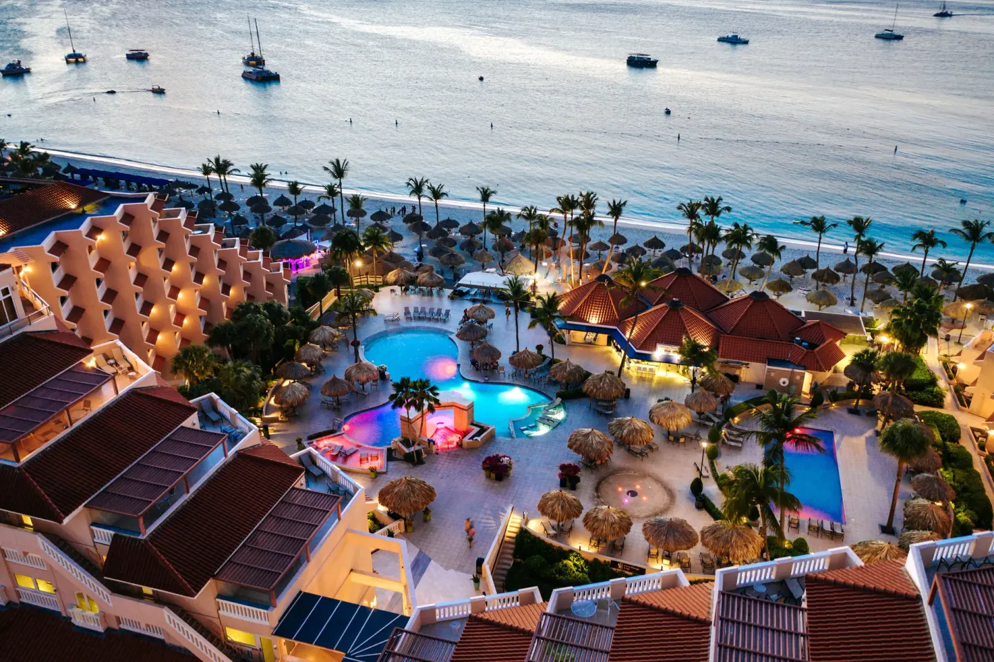 Evening aerial of lit pools and beachfront at Playa Linda Beach Resort.