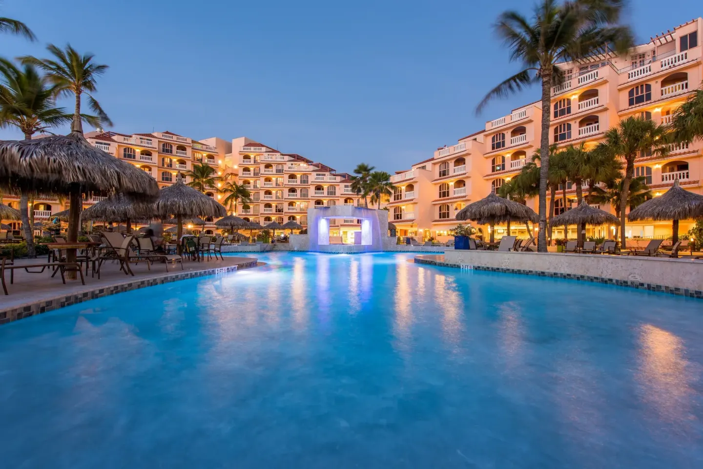 Evening pool courtyard with lit resort buildings at Playa Linda Beach Resort.