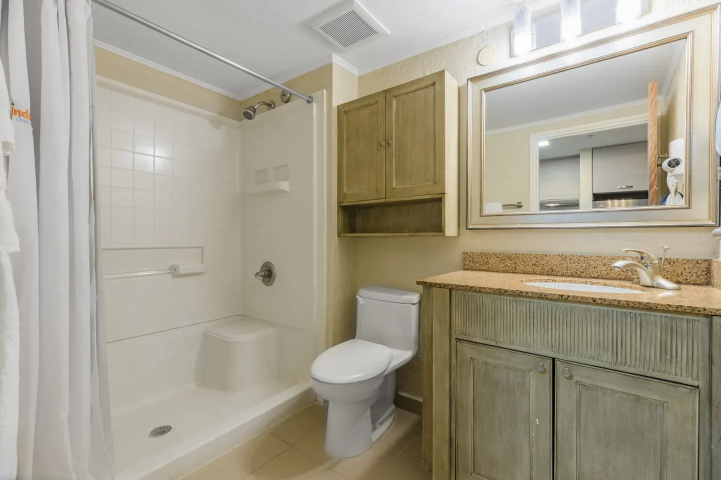 Guest bathroom with shower, toilet, vanity, and mirror at Playa Linda Beach Resort.