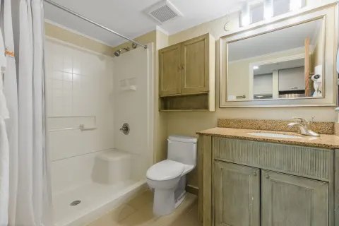 Guest bathroom with shower, toilet, vanity, and mirror at Playa Linda Beach Resort.