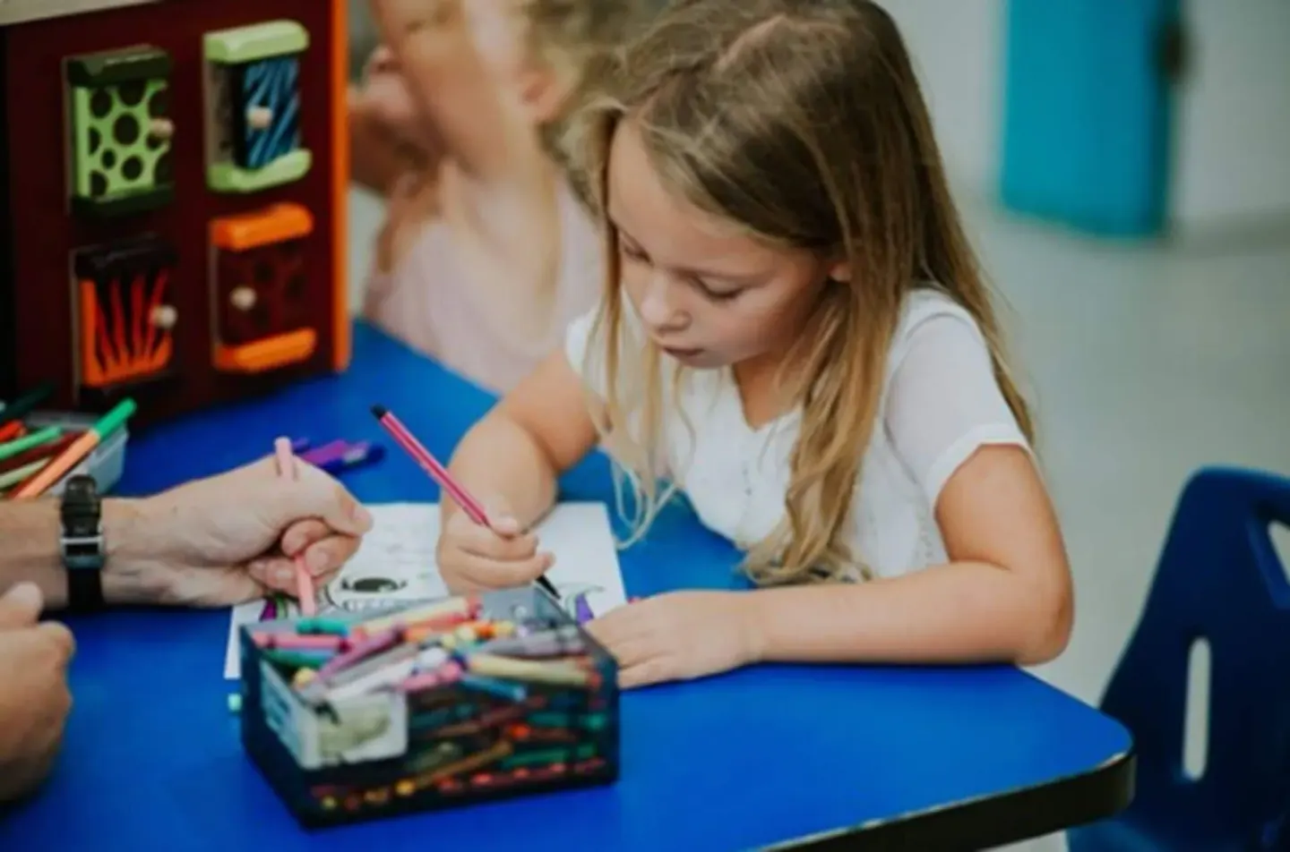 Child coloring at a blue table in the kids area at Playa Linda Beach Resort.