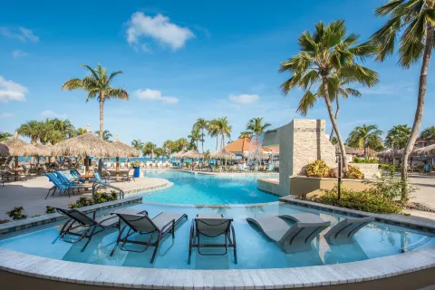 Main pool with in-water loungers, palapas, and palm trees at Playa Linda Beach Resort.
