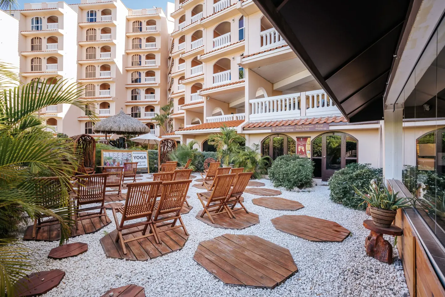 Outdoor courtyard with wooden chairs and resort buildings at Playa Linda Beach Resort.