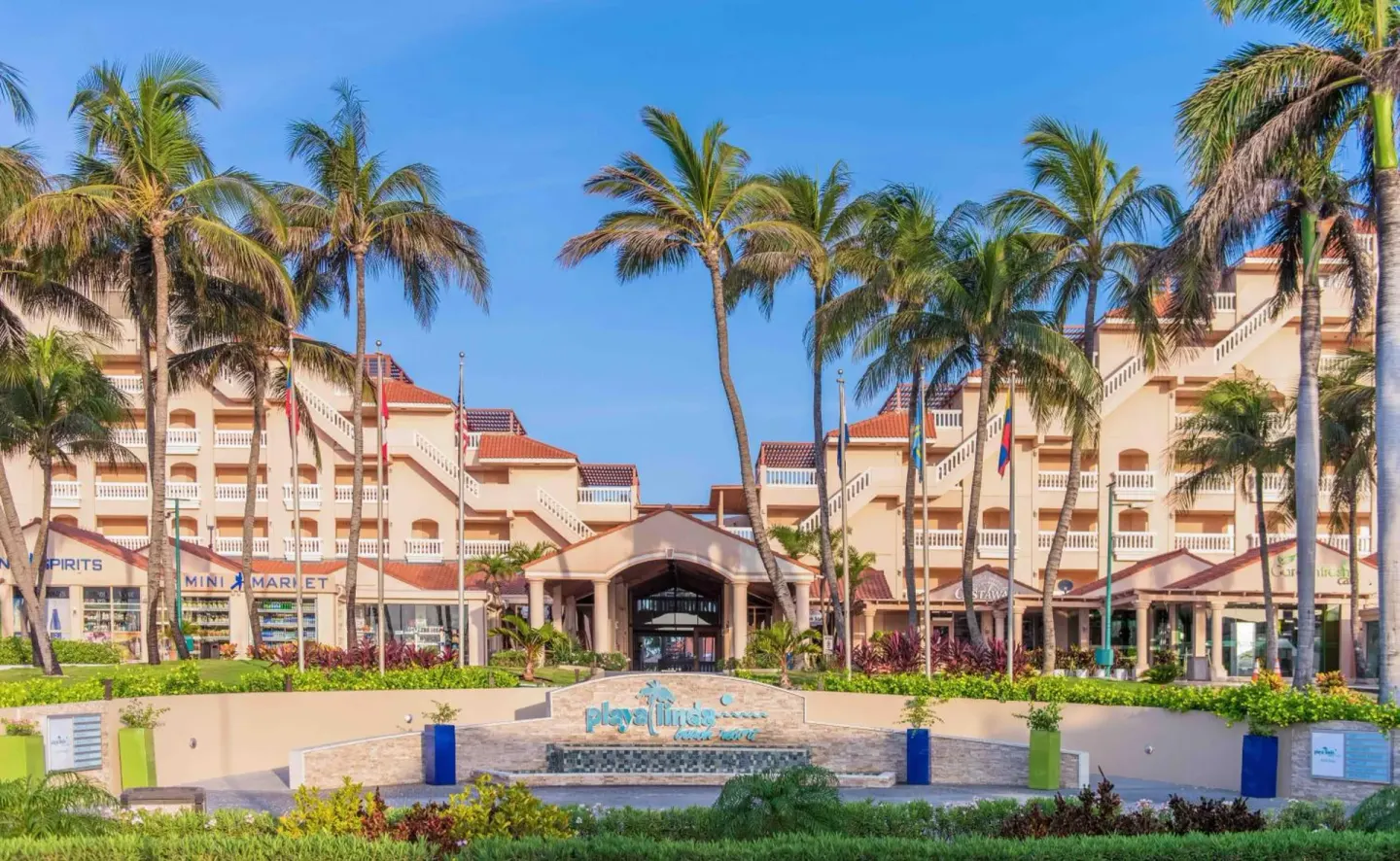 Palm-lined entrance and resort facade at Playa Linda Beach Resort.