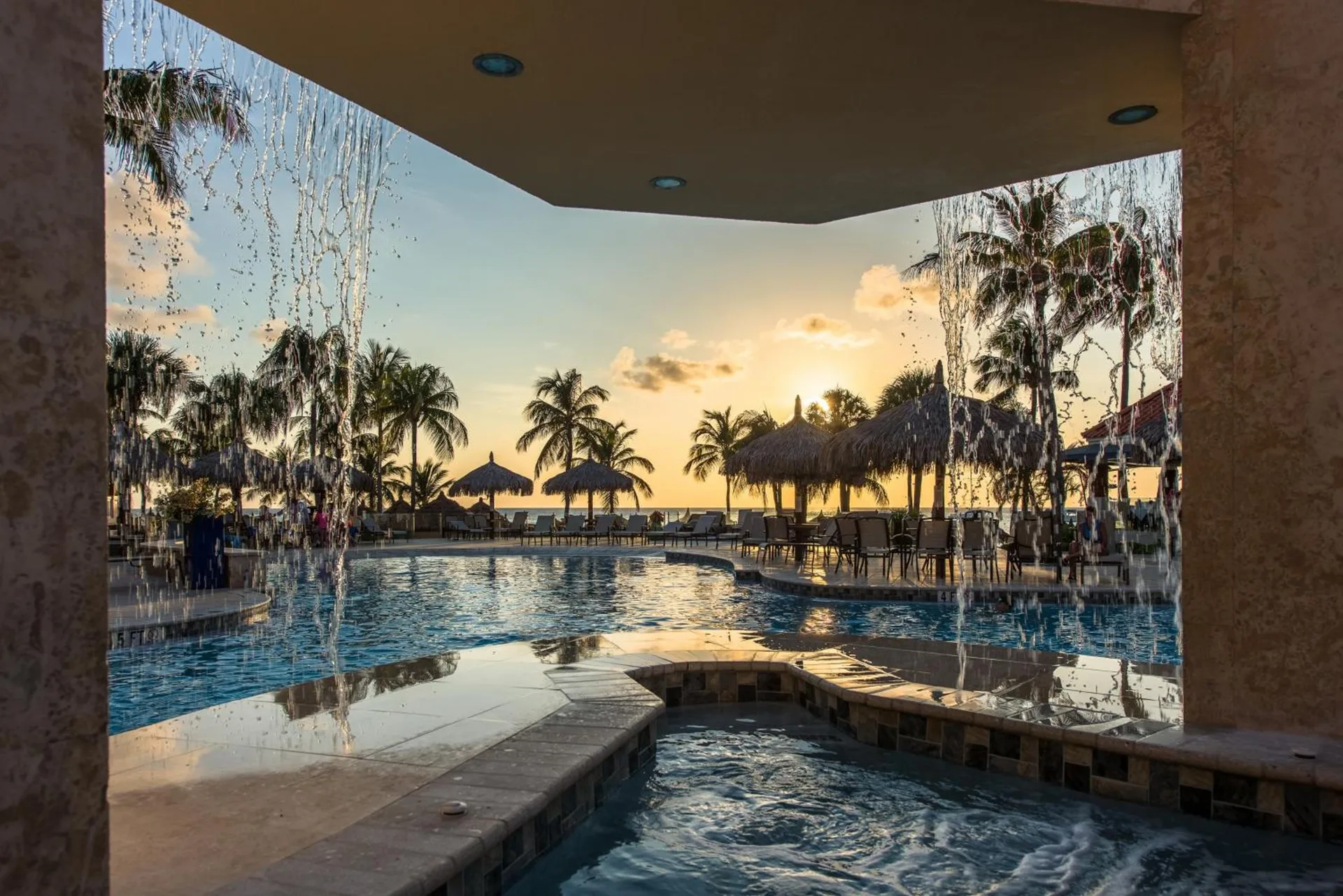 Pool and hot tub at sunset with waterfalls at Playa Linda Beach Resort.
